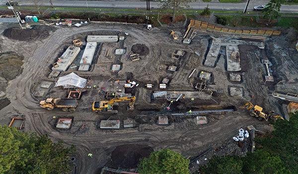 aerial view of construction with equipment digging and concrete rectangles