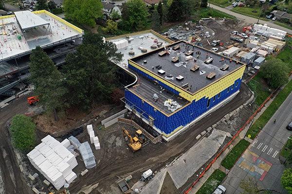 Part of a building under construction with blue and yellow material on the exterior