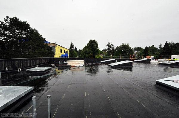 a flat roof with black material and skylights