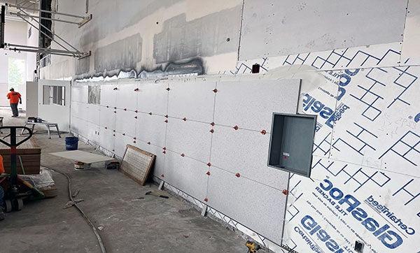Large wall tiles being installed on tile backer board on the wall