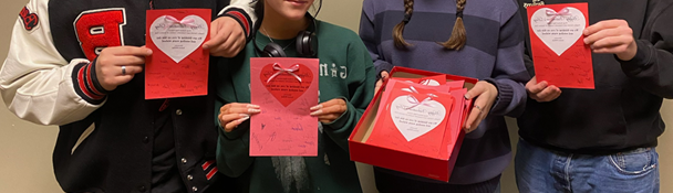 Four students holding Valentine's Day cards