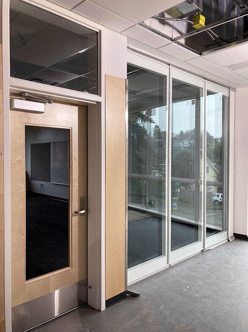 Three panels of tall windows reach all the way to the floor with a door in the wall next to them