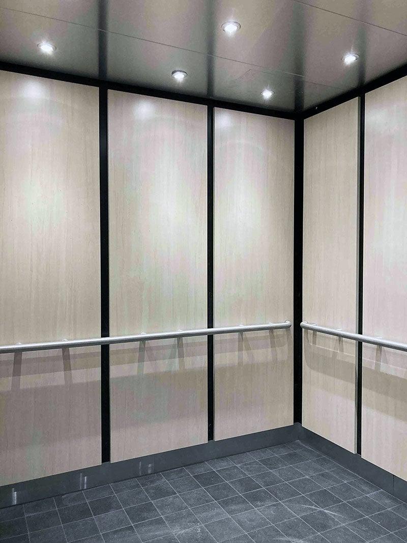 the inside of an elevator has squares on the floor and a railing around the walls